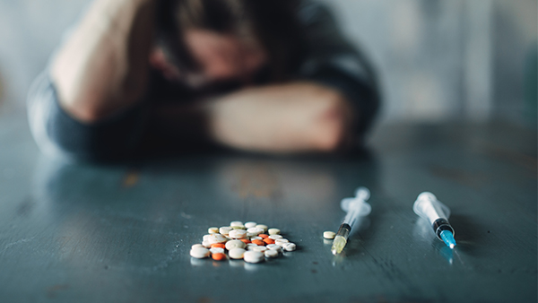 Drug addict with pills and syringe