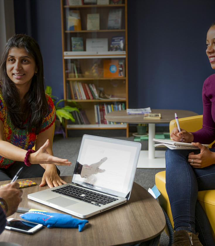Four Master of Public Health (MPH) students are sitting around a table and laptop while discussing a class assignment.
