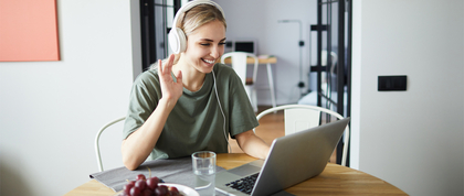 Woman waving at a laptop screen on a video call